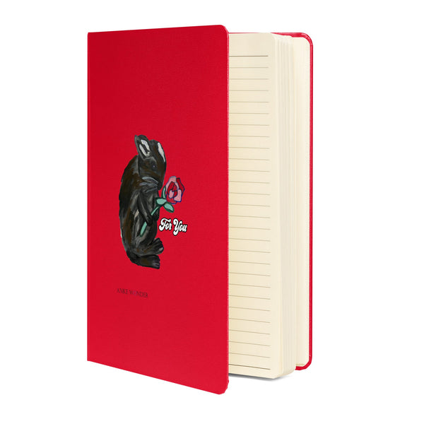 Standing, open view of a red notebook featuring a whimsical bunny holding a rose on the cover. The cream-colored lined pages are visible.