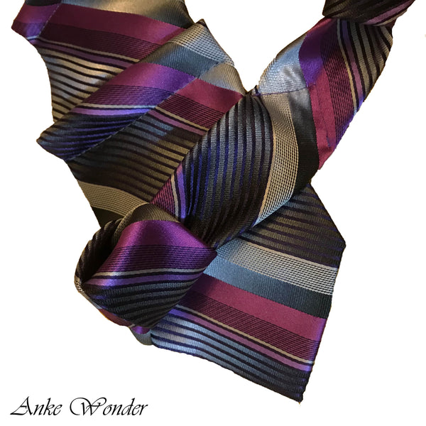 lose-up of a purple silk necktie with geometric patterns and pyramid pleats on a white background, highlighting eco-friendly craftsmanship from repurposed materials.