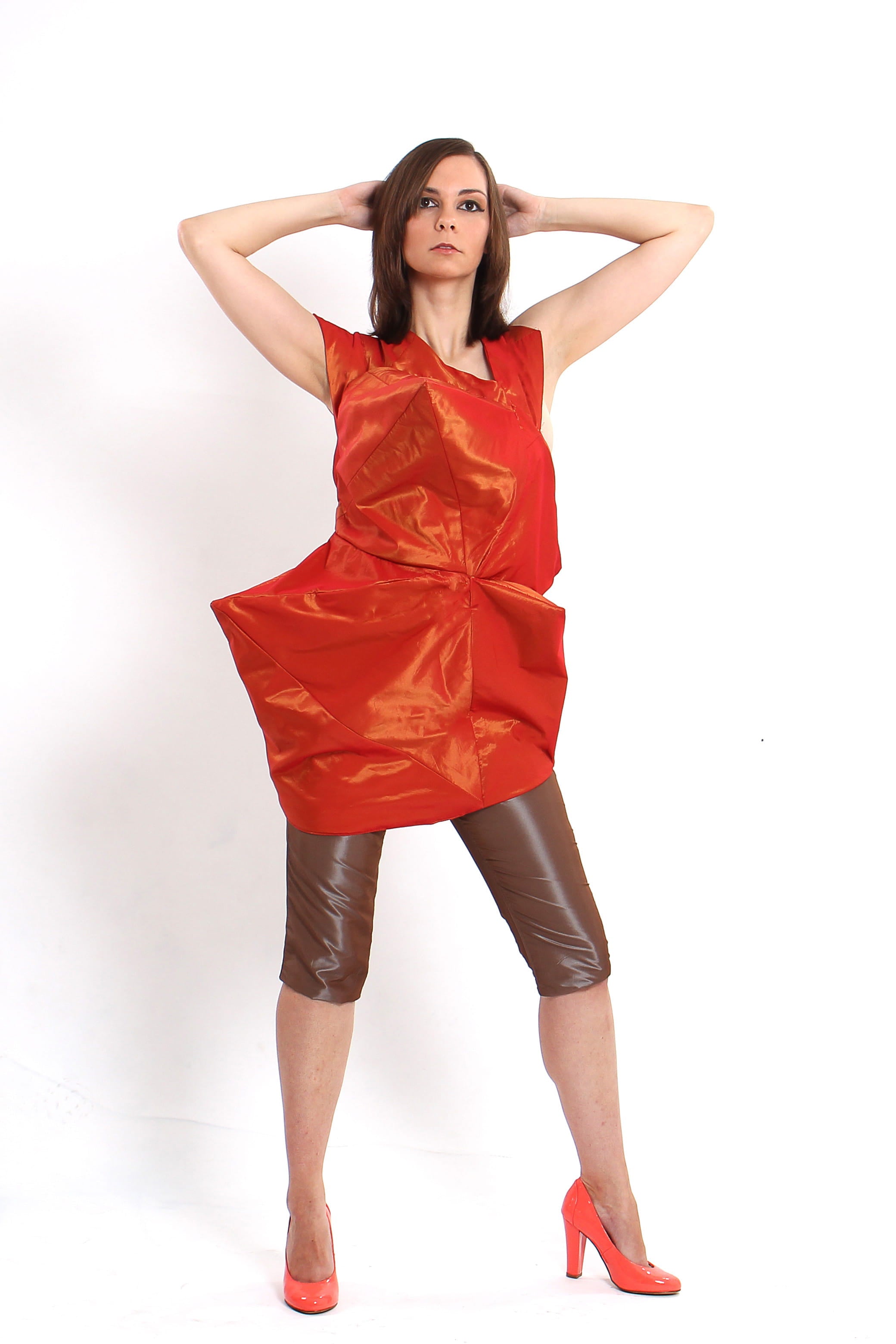 Woman wearing a red dress and brown leather shorts on a white background