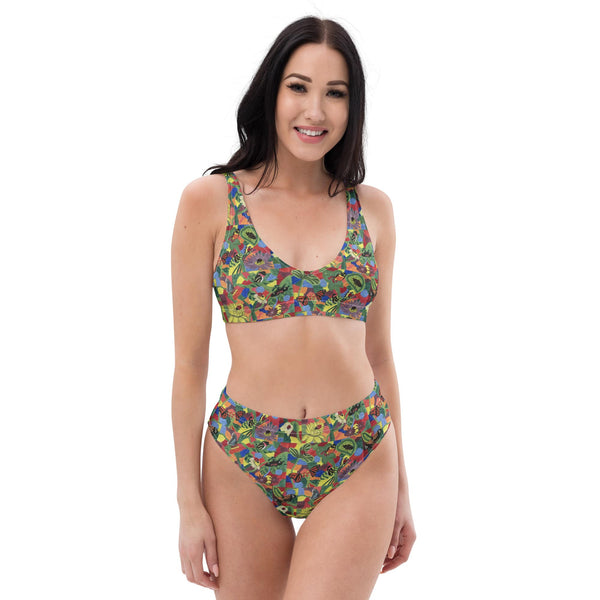 Model wearing a vibrant recycled high-waisted bikini with hand-painted butterfly, flower, and insect designs, smiling confidently against a white background.