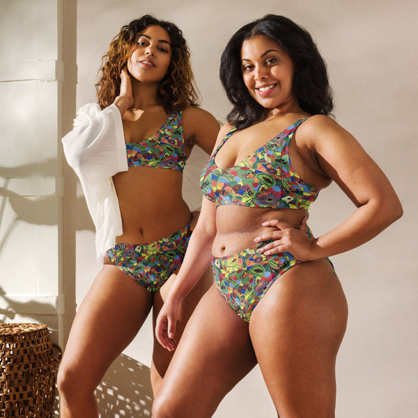 Models enjoying the outdoors in a recycled high-waisted bikini with bold butterfly and flower artwork, combining art, sustainability, and UPF 50+ sun protection.