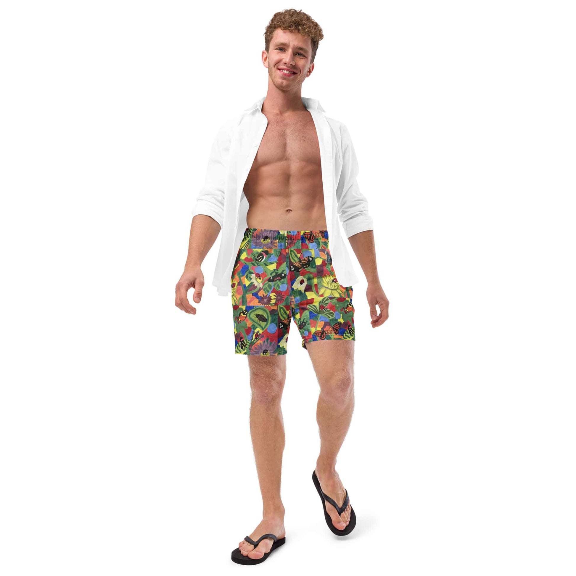 Model wearing men’s swim trunks with a floral butterfly design, paired with a white shirt.