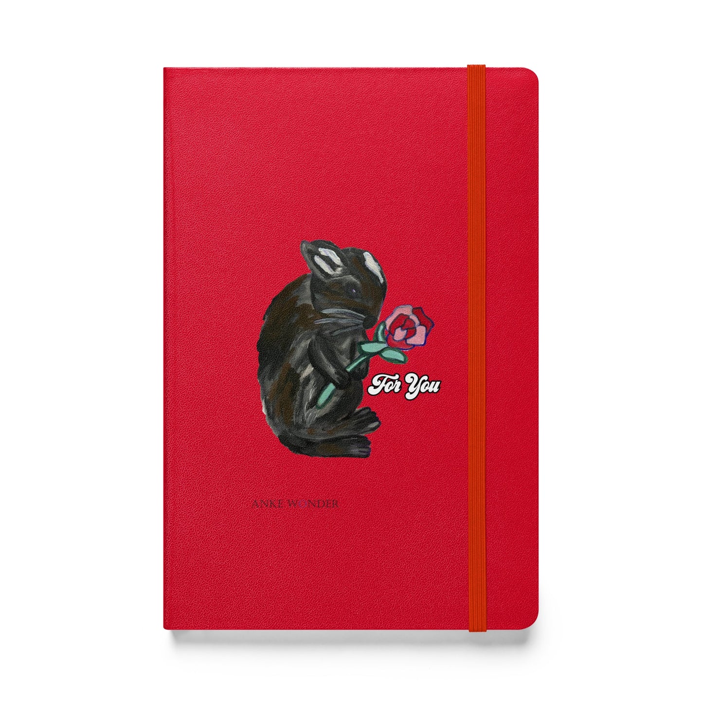 A red notebook featuring a whimsical illustration of a bunny holding a rose, with the phrase "For You" designed by Anke Wonder.
