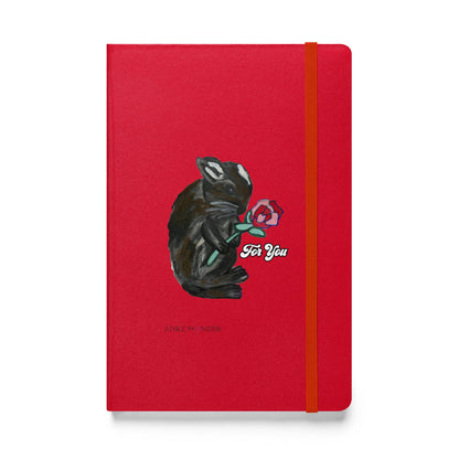 A red notebook featuring a whimsical illustration of a bunny holding a rose, with the phrase "For You" designed by Anke Wonder.