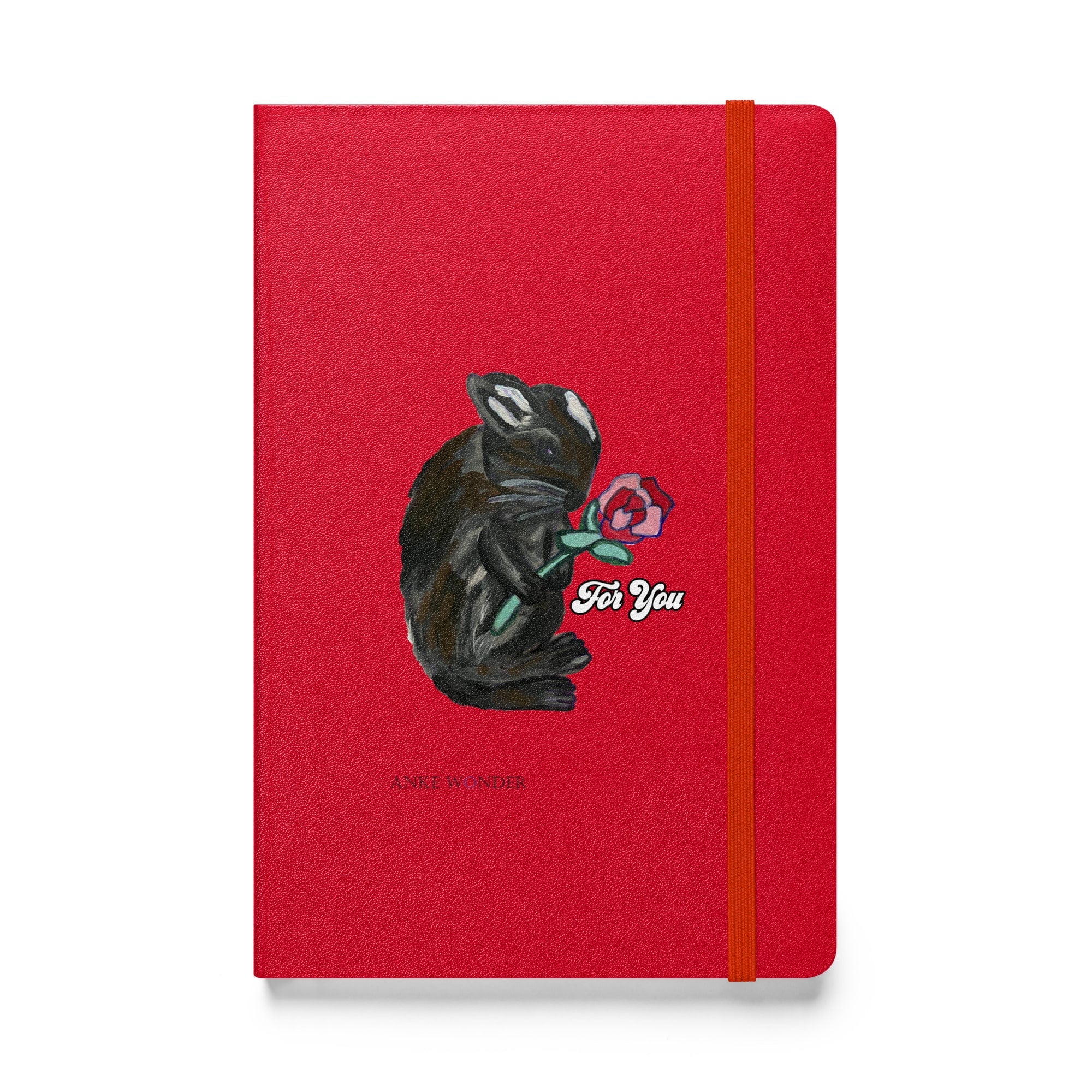 A red notebook featuring a whimsical illustration of a bunny holding a rose, with the phrase "For You" designed by Anke Wonder.