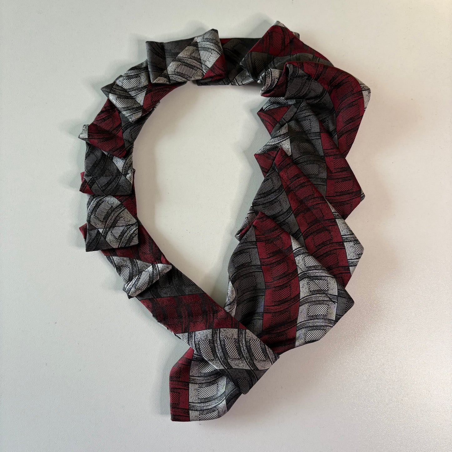 Plaid patterned red and silver tie on a mannequin with a plain background