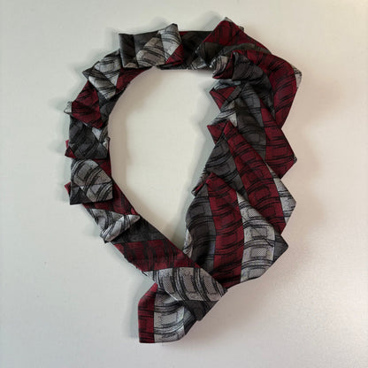 Plaid patterned red and silver tie on a mannequin with a plain background