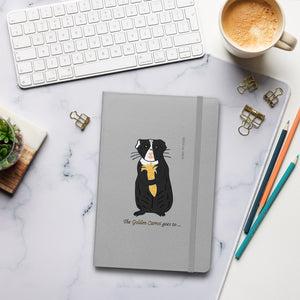 The Golden Carrot Guinea Pig Notebook resting on a desk, surrounded by a coffee mug, pencil, and keyboard, perfect for journaling and personal growth reflections designed by Anke Wonder.