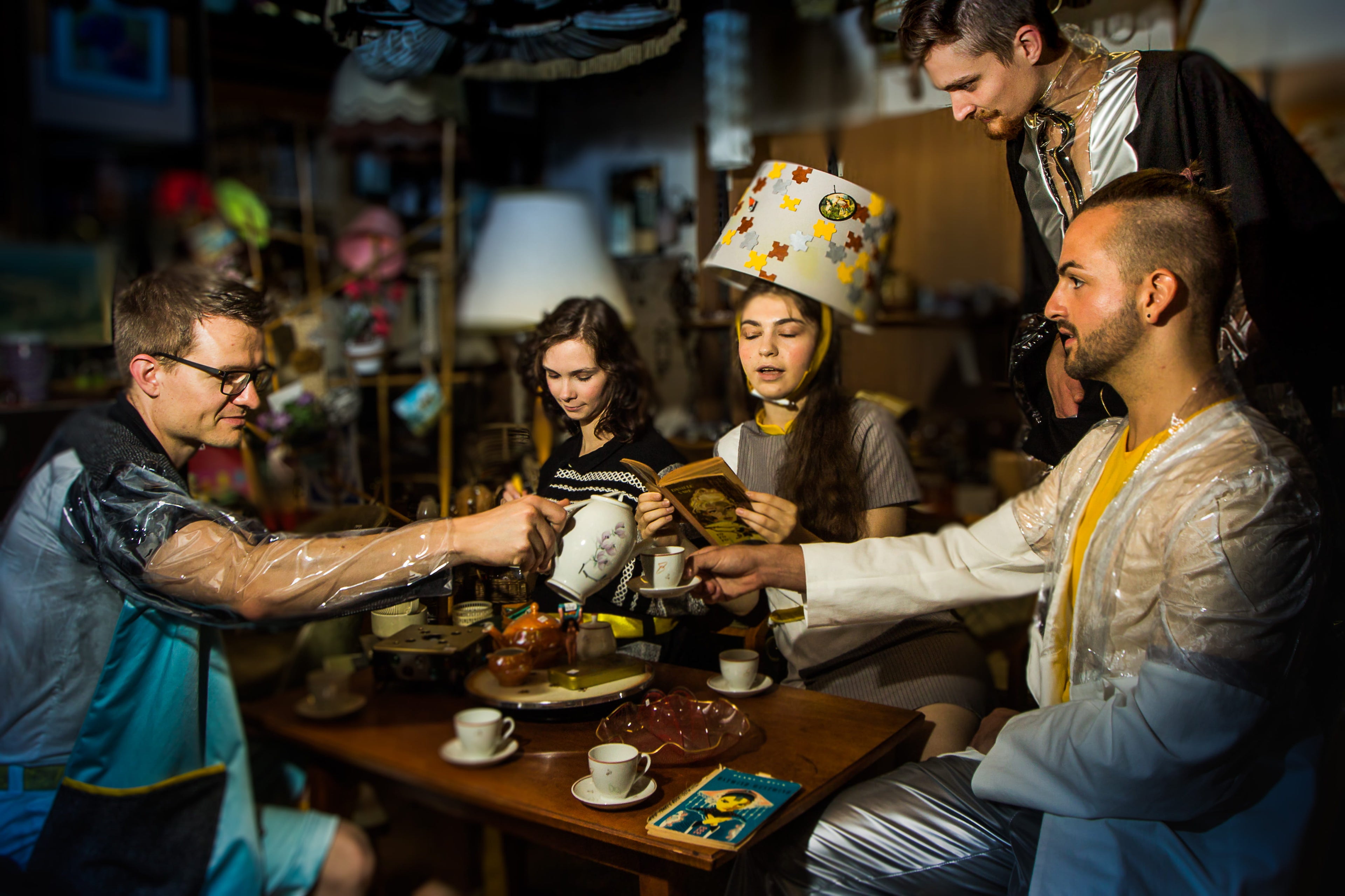 Group of people gathered around a table in a cozy indoor setting, possibly a cafe or restaurant.