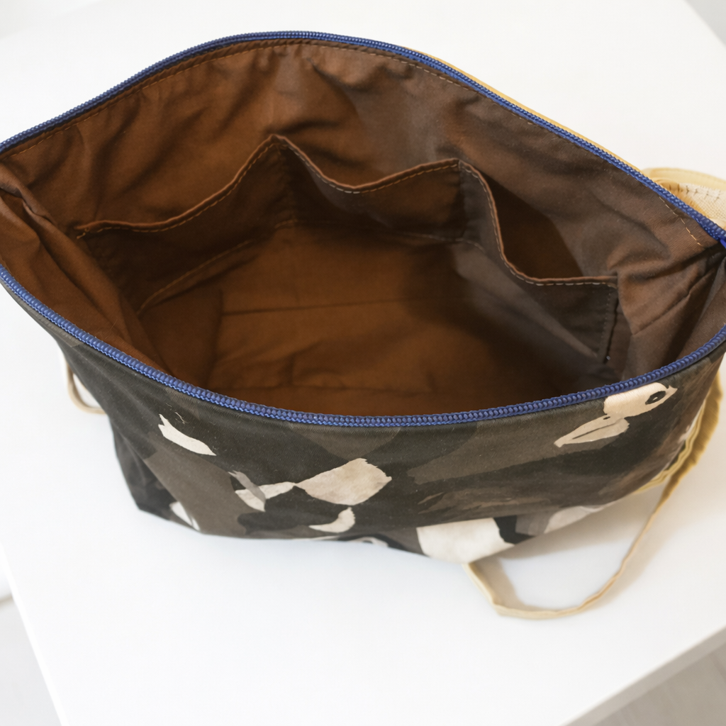 Open bag with camouflage bird pattern and blue interior on a white background