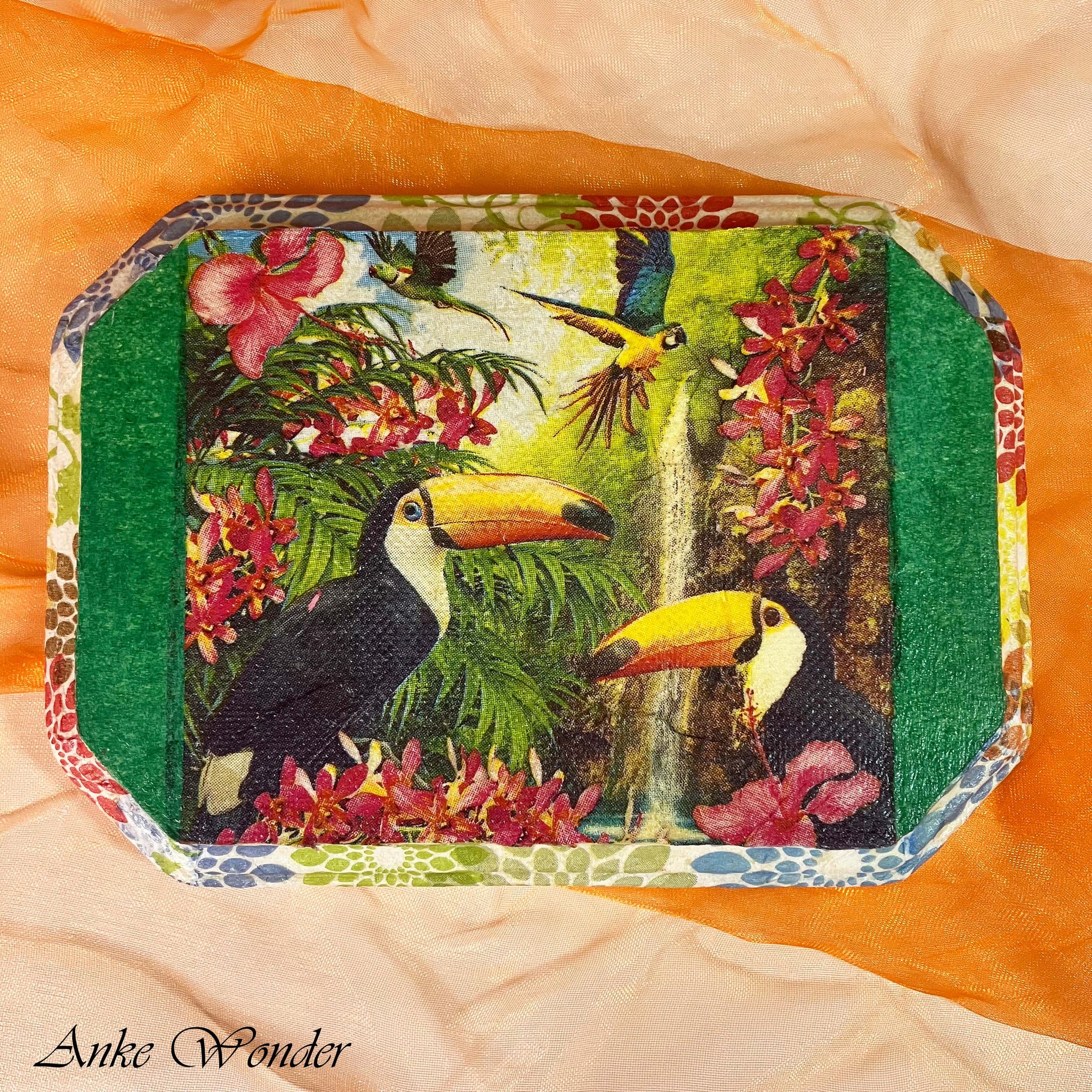 Front view of handmade wooden wall art featuring a vibrant decoupage collage of toucans, tropical flowers, and a jungle backdrop.