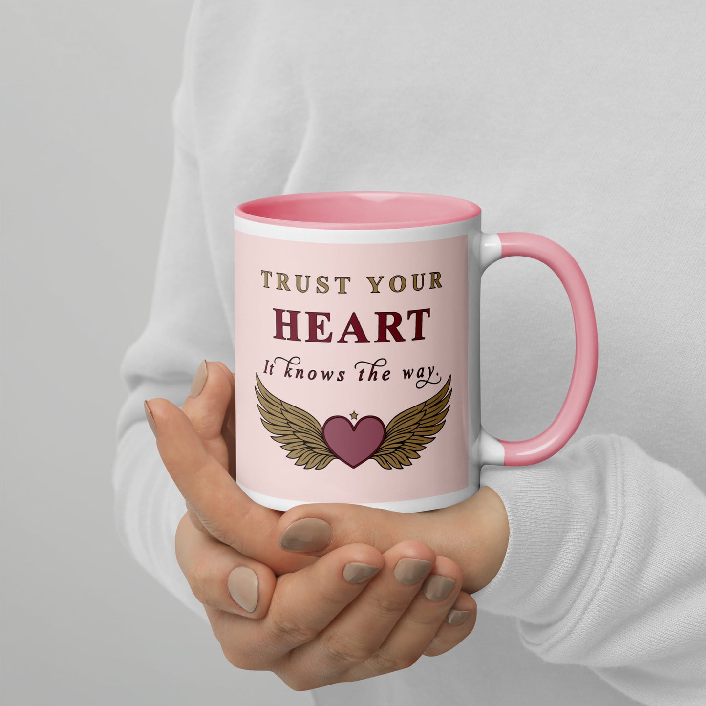 Person holding a pink mug with motivational quote and heart design