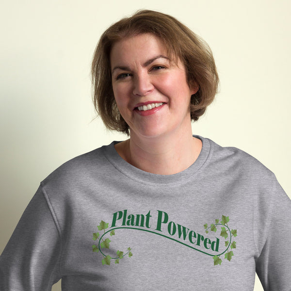 Close-up of a woman wearing a green sweatshirt featuring the 'Plant Powered' print surrounded by an elegant ivy leaf design.