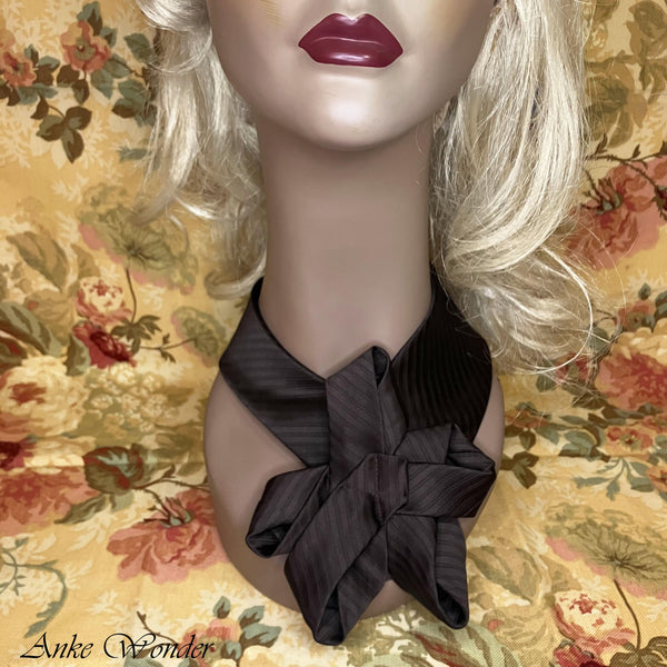 Closeup of a handmade brown necktie with a floral-inspired design on a mannequin, showcasing its detailed craftsmanship.