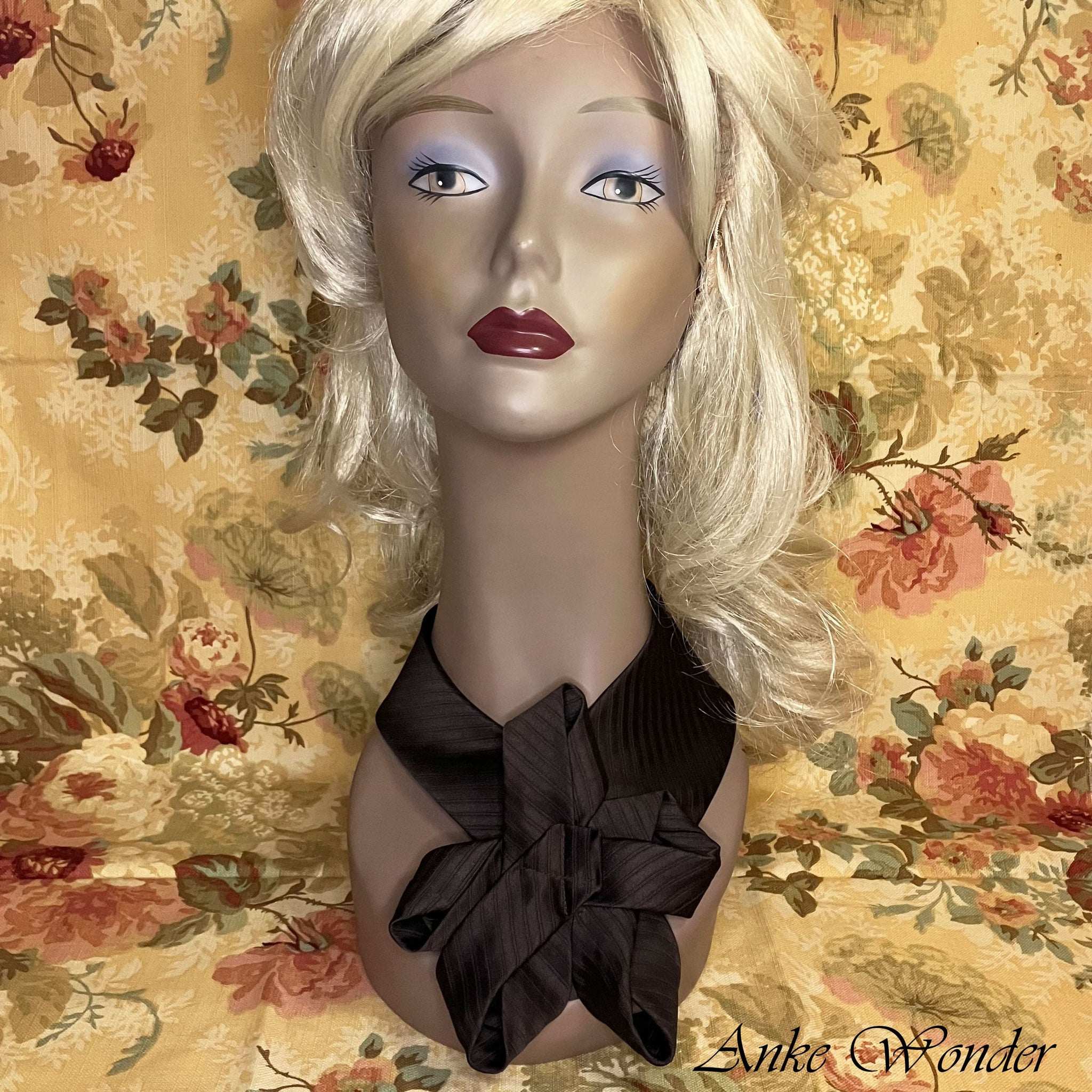 Handmade brown necktie with a floral-inspired design on a mannequin, showcasing its detailed craftsmanship.