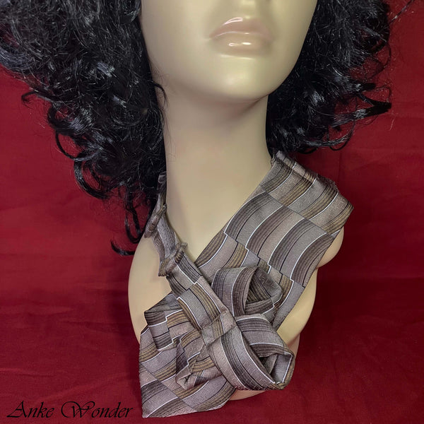 Close-up of a handmade women's gray silk necktie with pleated striped design on a mannequin.