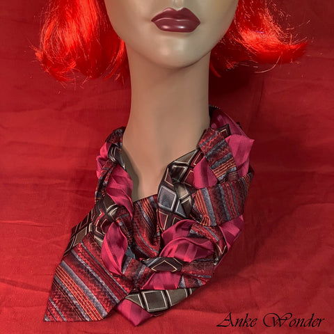 Close-up of a red and silver women's necktie on a mannequin, showcasing the intricate weaving design and sustainable craftsmanship using upcycled ties.