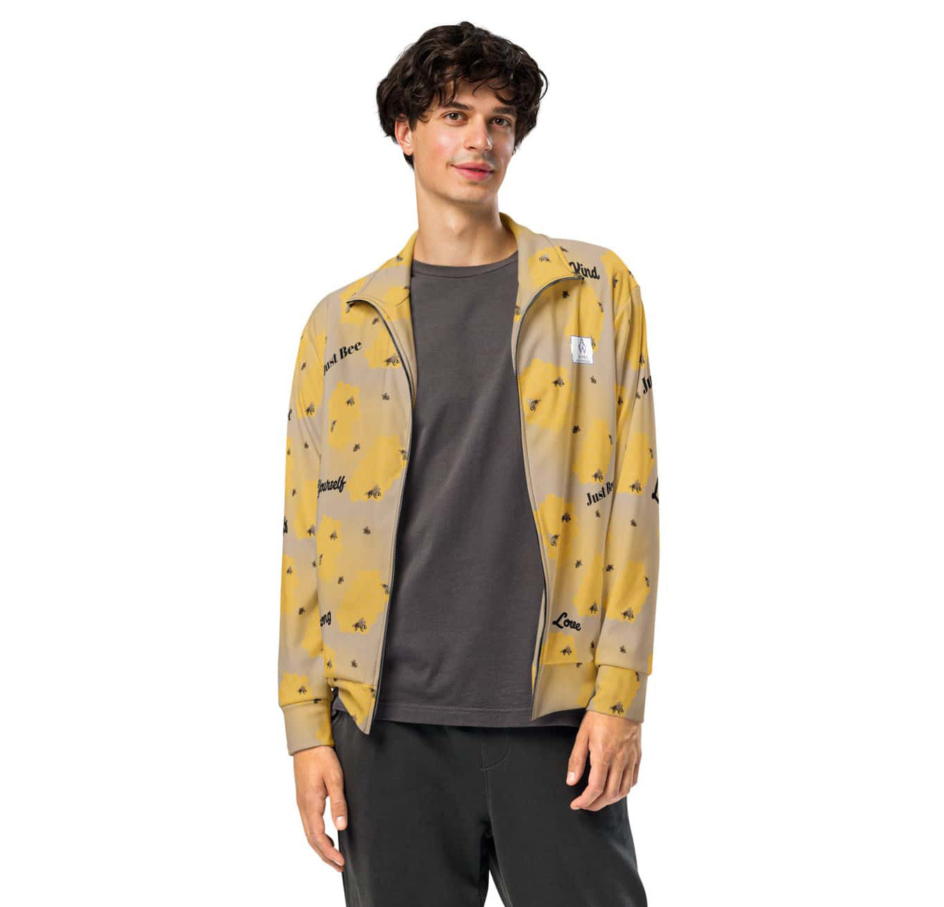Men’s track jacket with bee and honeycomb design, featuring affirmations like “Just Bee,” “Kind,” and “Love” on recycled fabric.