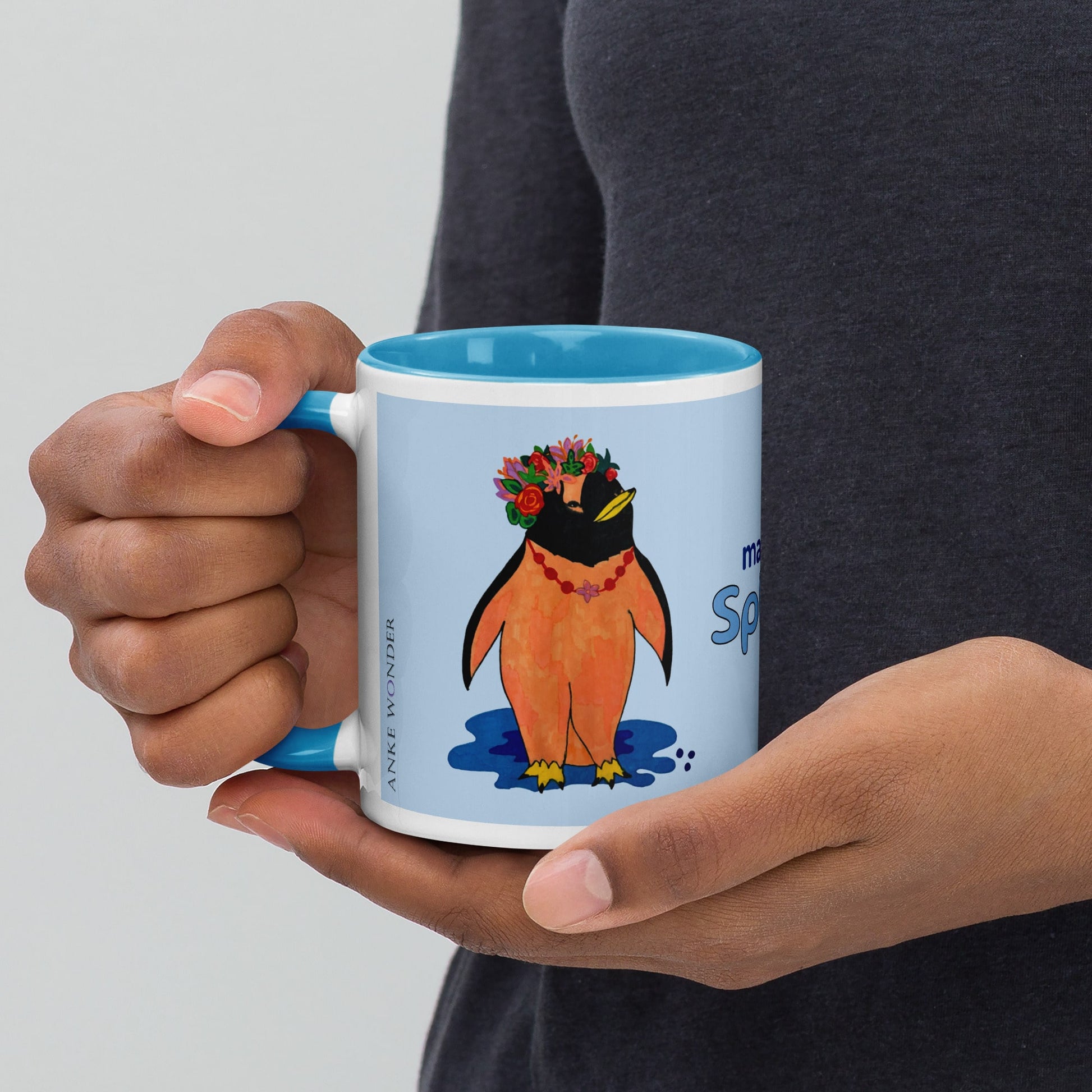 Person holding a blue mug with a penguin design on a light gray background