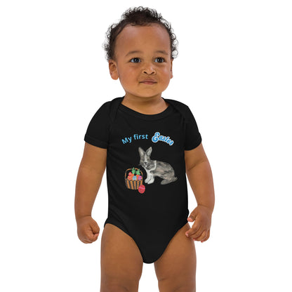 A baby boy wearing a black short-sleeve organic cotton bodysuit with a bunny and Easter basket graphic, plus the text 'My First Easter' in blue.