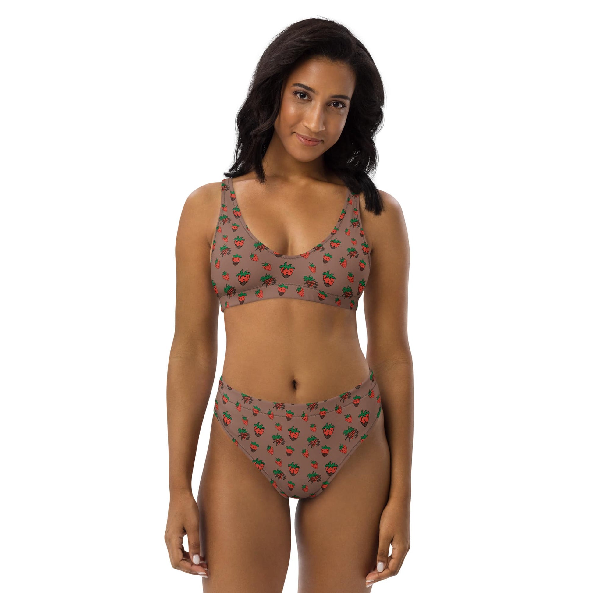 Woman wearing a strawberry print high-waisted bikini made from recycled fabric, shown from the front with a relaxed smile and natural pose.