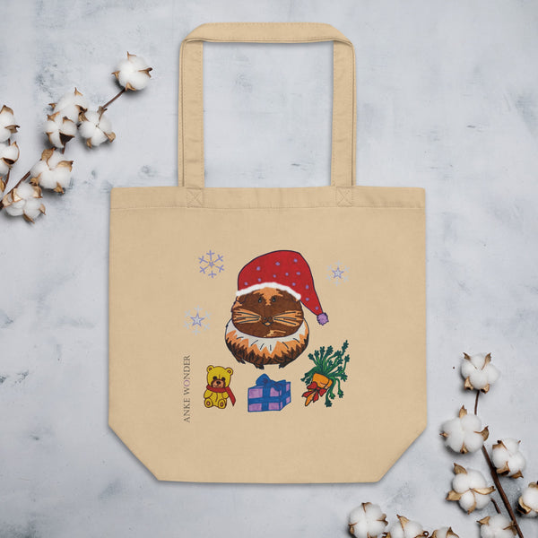 Beige tote bag with festive design featuring a guinea pig in a Santa hat, surrounded by Christmas elements on a light gray background.