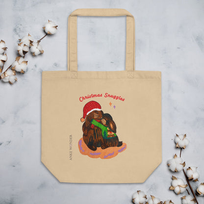 Beige tote bag with Christmas-themed design of two rabbits hugging, surrounded by cotton branches on a light gray background.