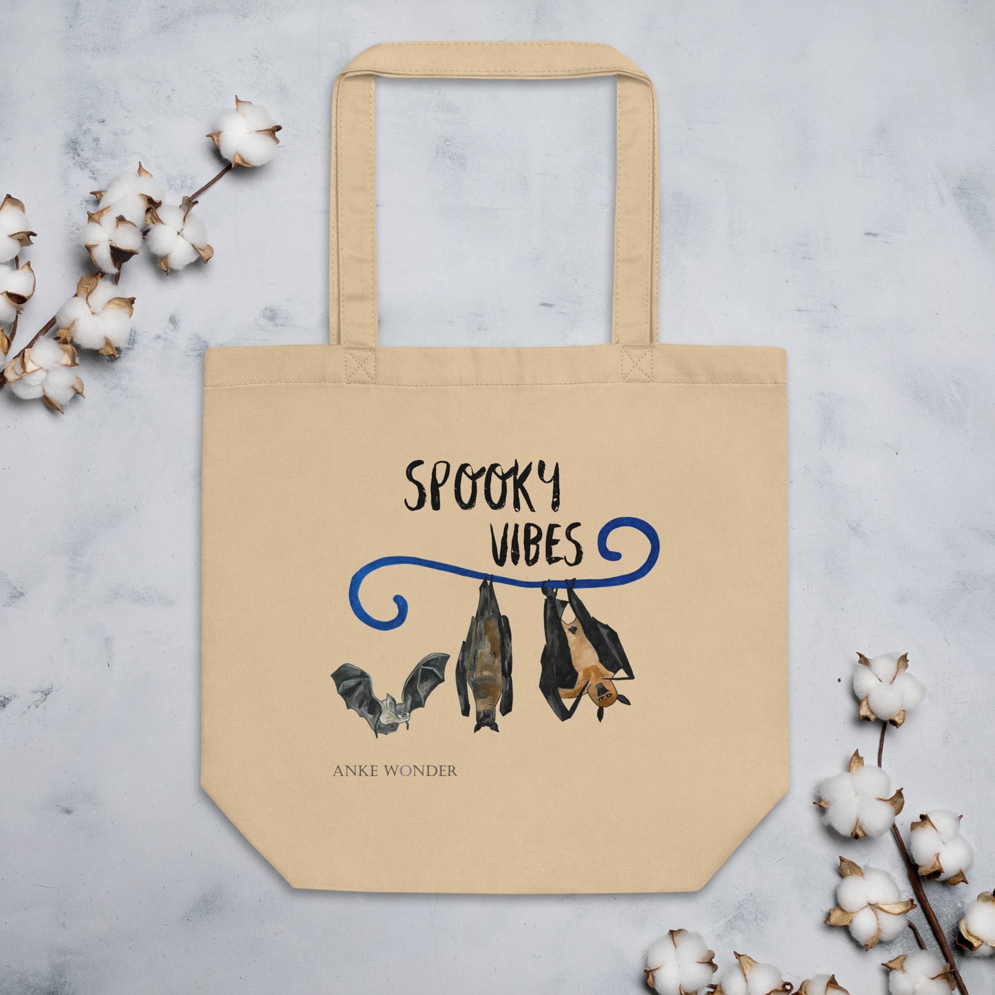 Beige tote bag with 'Spooky Vibes' design featuring bats on a light gray background with cotton branches.