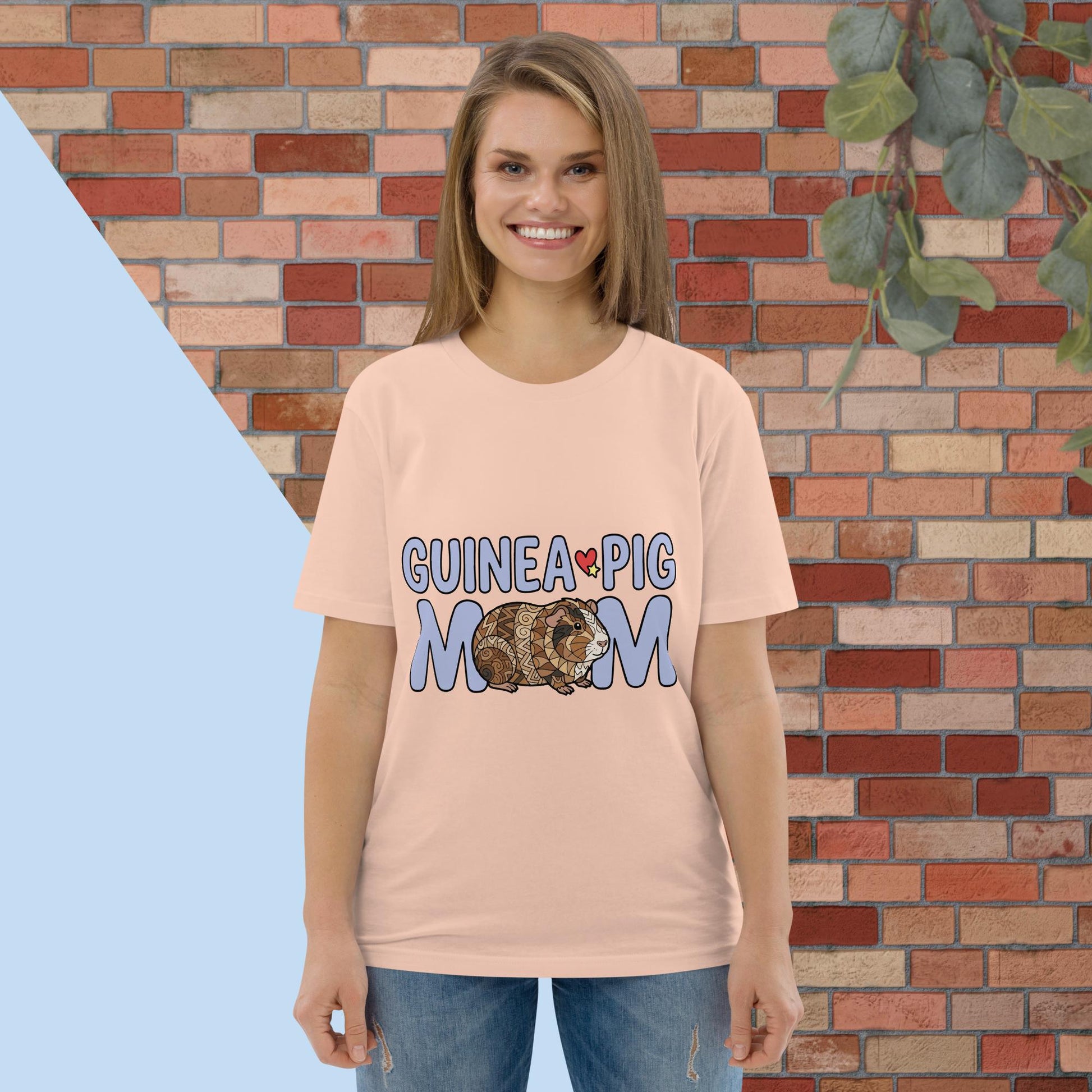 Woman wearing a 'Guinea Pig Mom' t-shirt in front of a brick wall.
