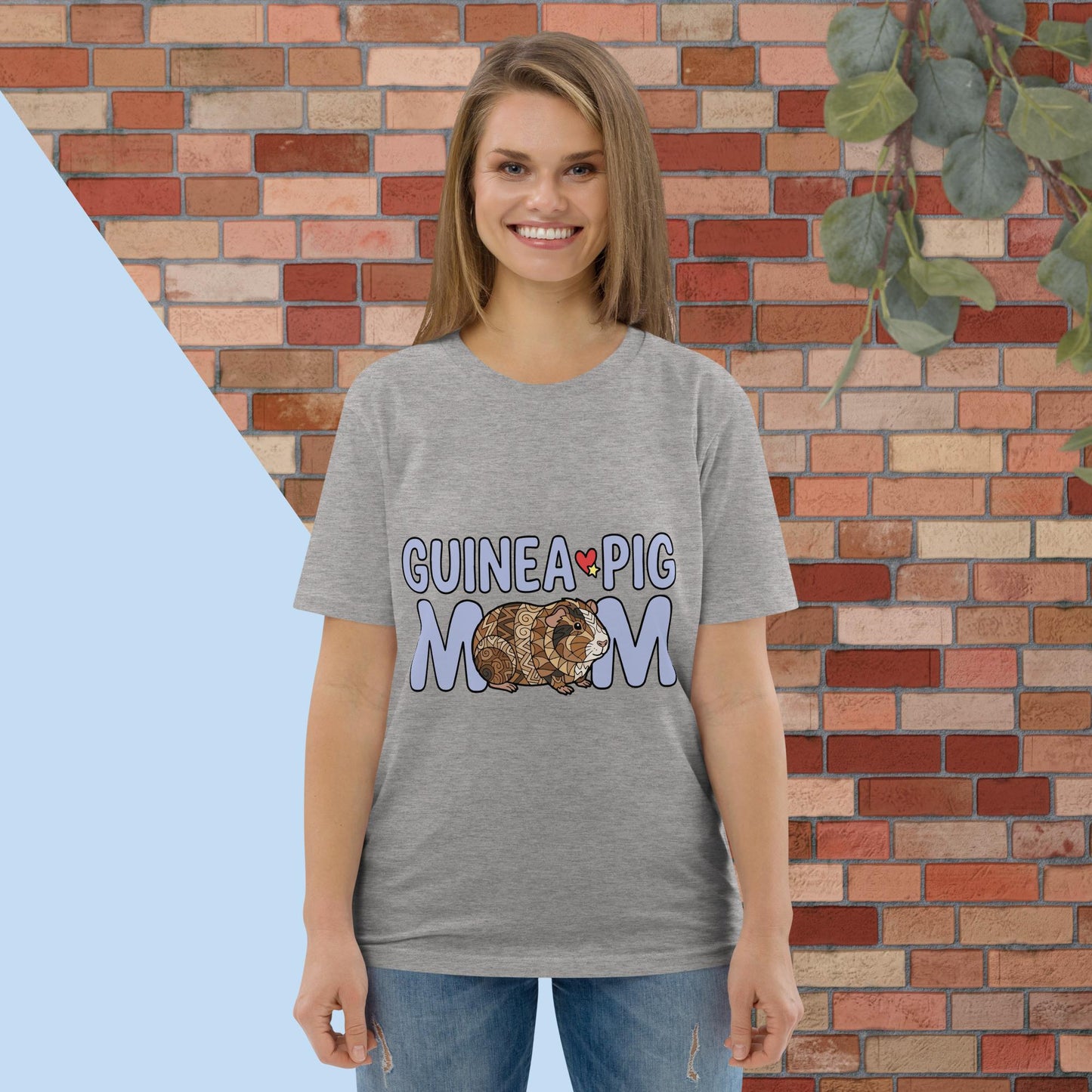 Woman wearing a gray t-shirt with 'Guinea Pig Mom' design against a brick wall.