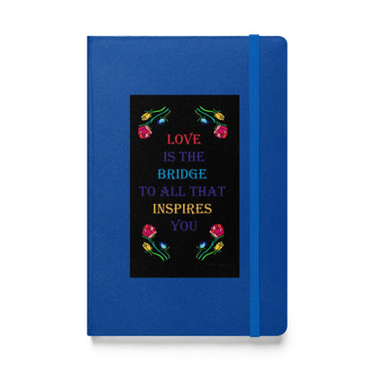 Front of hardcover notebook with blue binding featuring the quote "Love is the bridge to all that inspires you" in colorful text with roses designed by Anke Wonder.