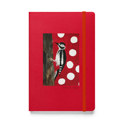 A red hardcover notebook with an elastic closure band, featuring a central illustration of a black-and-white woodpecker on a red background with white polka dots and the text 'ANKE Wonder' printed near the bottom.