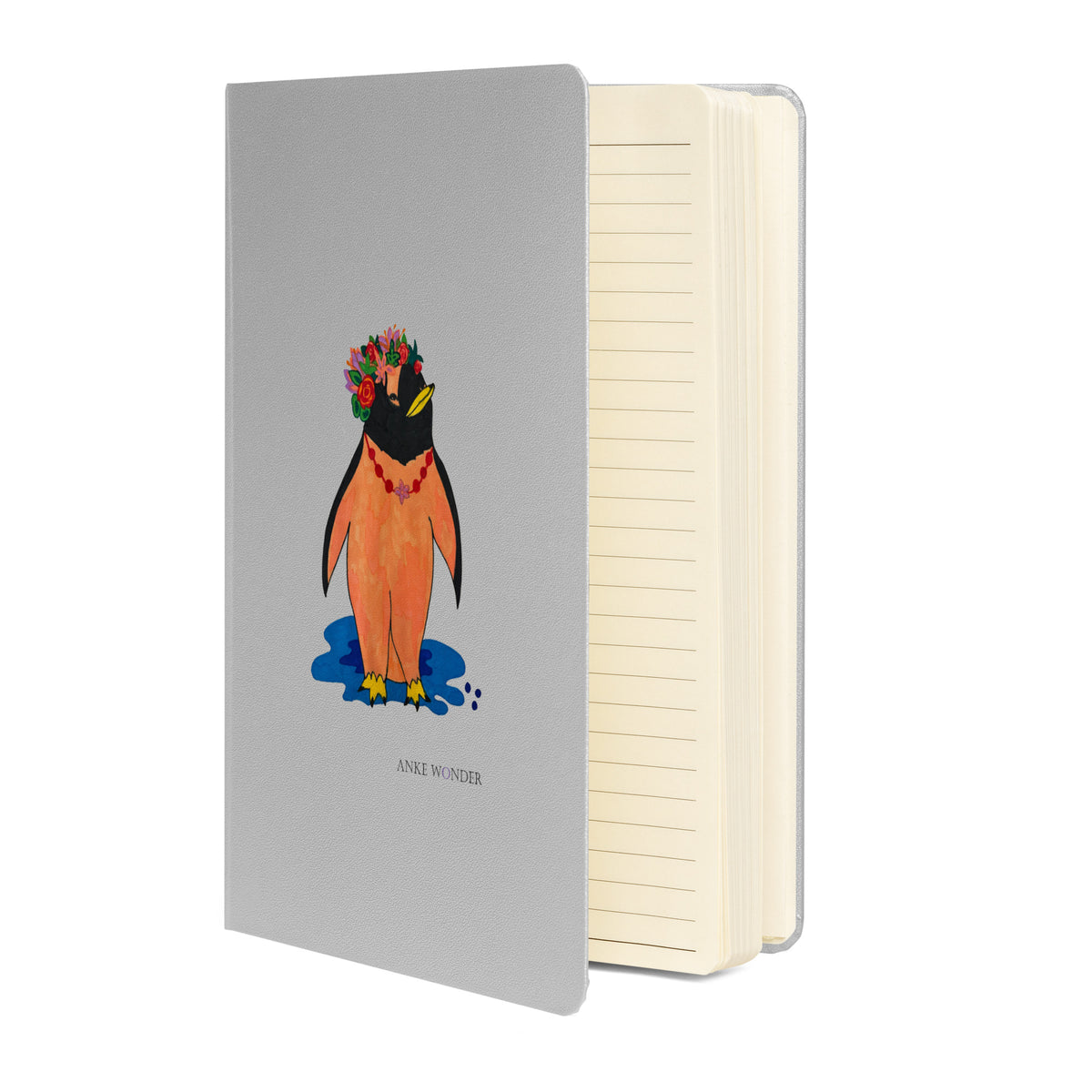 Open grey notebook with colorful artistic penguin notebook with a silver-grey hardcover, featuring a stylized orange penguin wearing a vibrant floral crown standing above a blue shadow.