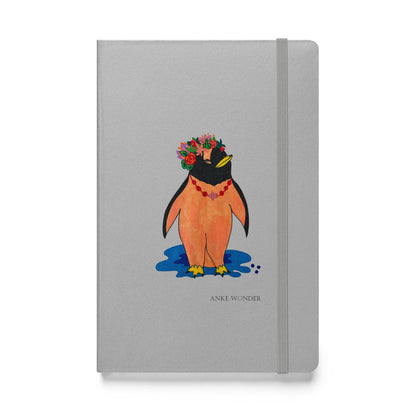 Colorful artistic penguin notebook with a silver-grey hardcover, featuring a stylized orange penguin wearing a vibrant floral crown standing above a blue shadow.