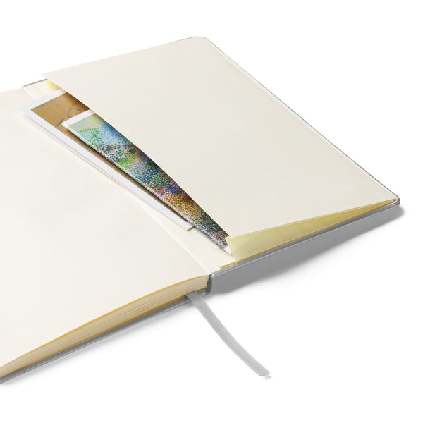 Inside view of the hardcover notebook featuring the expandable inner pocket for storing notes and keepsakes, alongside cream-colored lined pages.