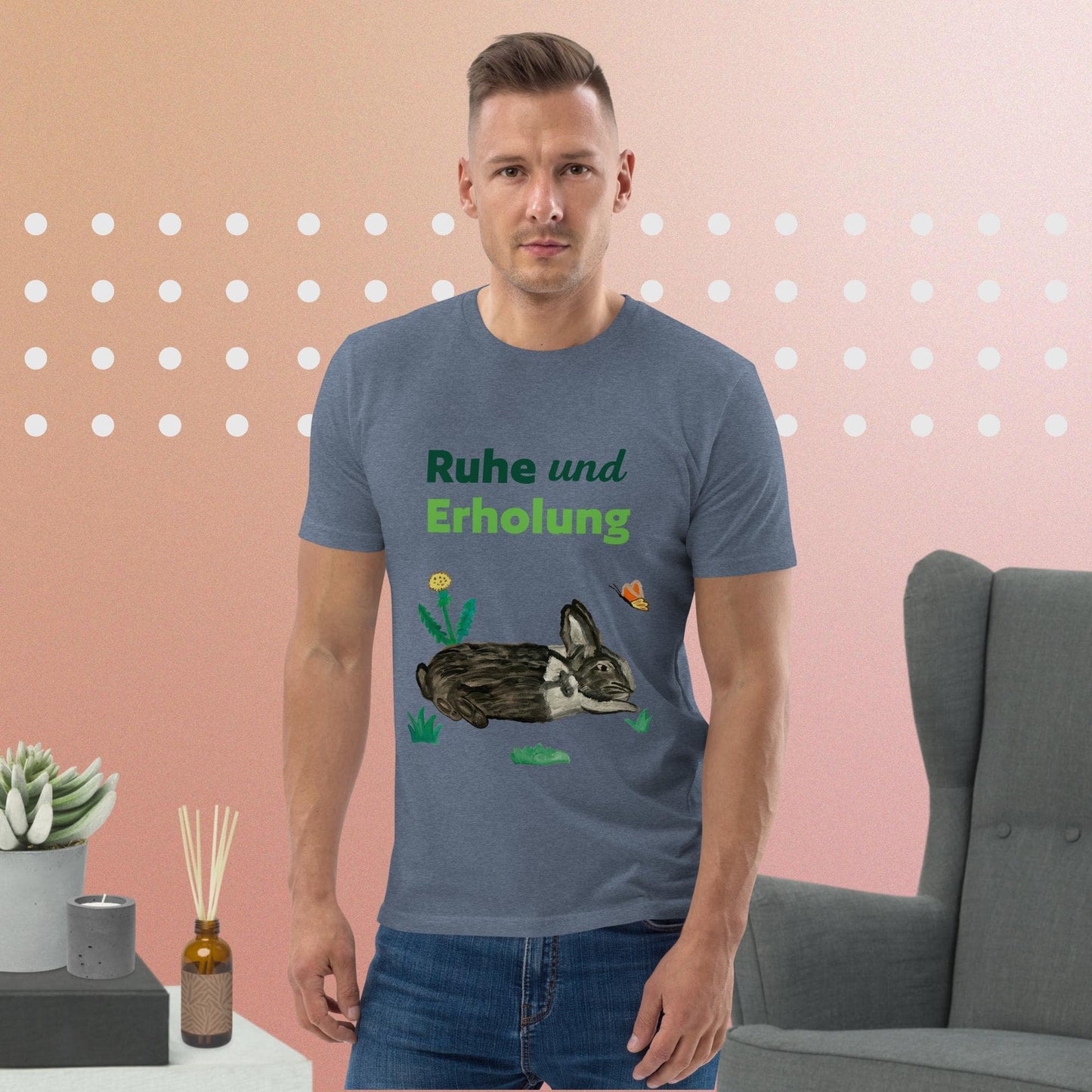 Man wearing dark heather blue organic cotton t-shirt featuring hand-painted black-and-white rabbit with butterfly and greens, and the words "Ruhe & Erholung" on the front.