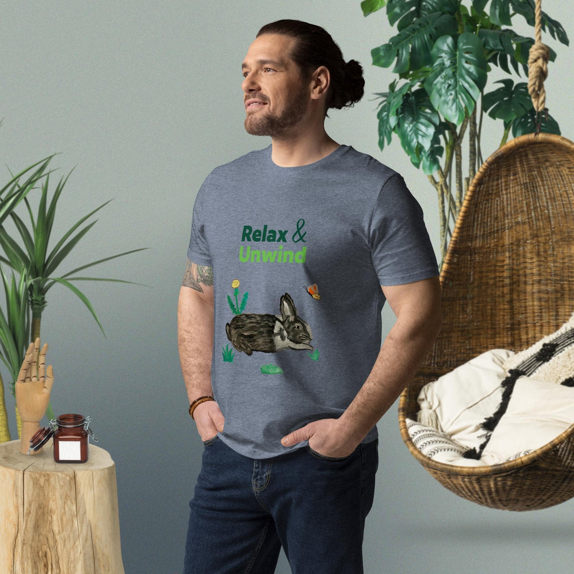 Man wearing dark heather grey organic cotton t-shirt with hand-painted black-and-white rabbit, greens, butterfly, and "Relax & Unwind" text — front view, right angle.