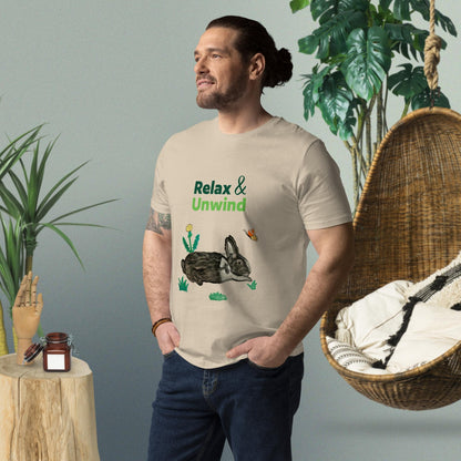 Man wearing desert dust organic cotton t-shirt with hand-painted black-and-white rabbit, greens, butterfly, and "Relax & Unwind" text — front view, right angle.