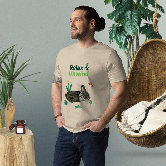Man wearing desert dust organic cotton t-shirt with hand-painted black-and-white rabbit, greens, butterfly, and "Relax & Unwind" text — front view, right angle.