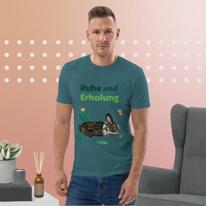 Man wearing organic cotton t-shirt in stargazer color featuring hand-painted black-and-white rabbit with butterfly and greens, and the words "Ruhe & Erholung" on the front.