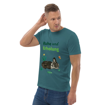 Man wearing organic cotton t-shirt at right angle in stargazer color, showing "Ruhe & Erholung" text and hand-painted rabbit, butterfly, and foliage design.