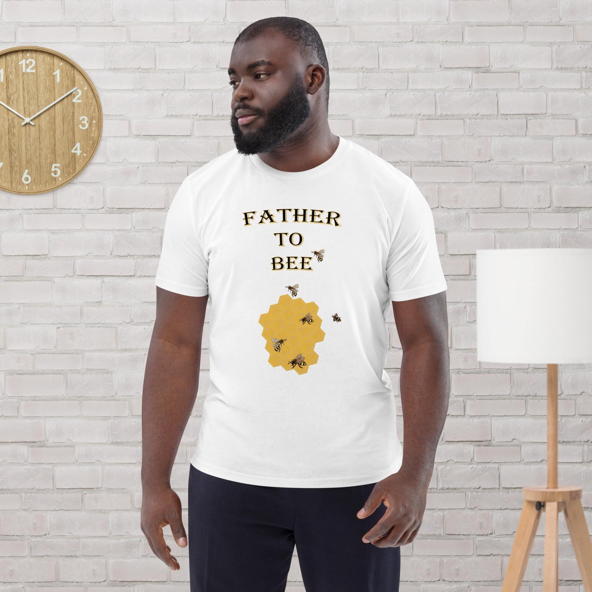 Man wearing a white organic cotton t-shirt with “Father to Bee” text and bee graphic, standing in a modern room.