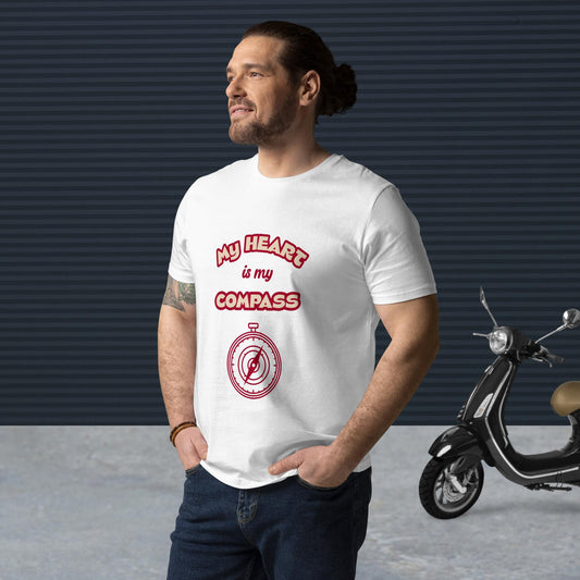 Man wearing white organic cotton t-shirt with red 'My Heart is My Compass' print, standing confidently near black Vespa scooter — sustainable spiritual fashion.