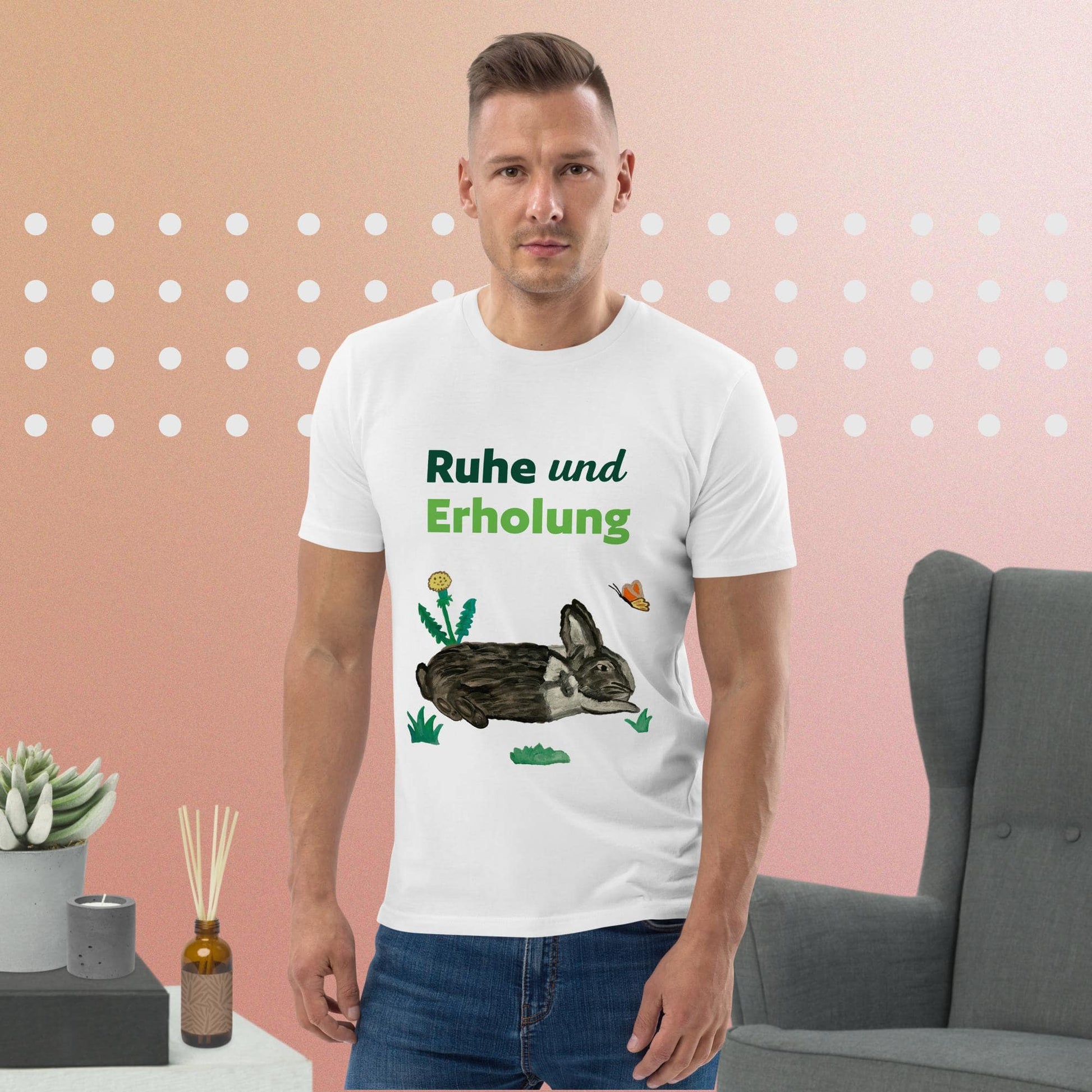 Man wearing white organic cotton t-shirt featuring hand-painted black-and-white rabbit with butterfly and greens, and the words "Ruhe & Erholung" on the front.