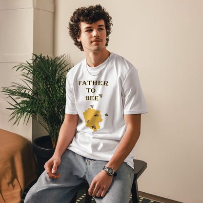 Man wearing a white “Father to Bee” organic cotton t-shirt at a slight front angle, standing in a cozy room setting.