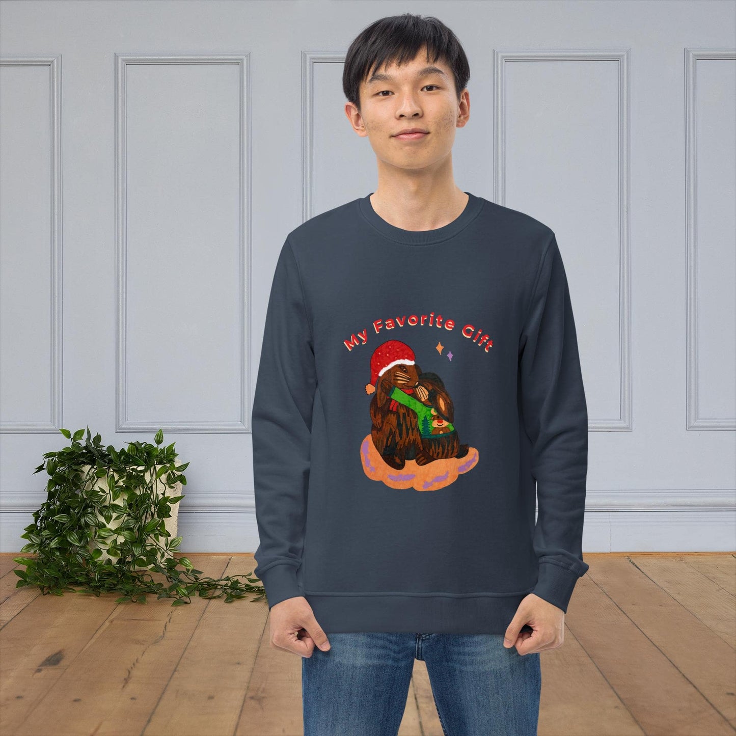 Man wearing a navy blue sweatshirt with a bunny christmas design in a room with a light gray wall and wooden floor.