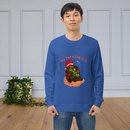 Man wearing a blue sweatshirt with a Christmas-themed bunny graphic and text 'My favorite gift' in a room with a plant and wooden floor.