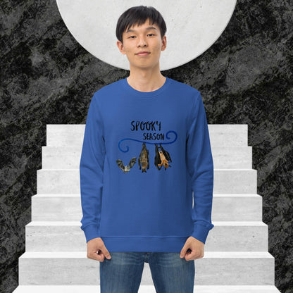 Man wearing a blue sweatshirt with 'Spooky Season' design and bat illustration on stairs