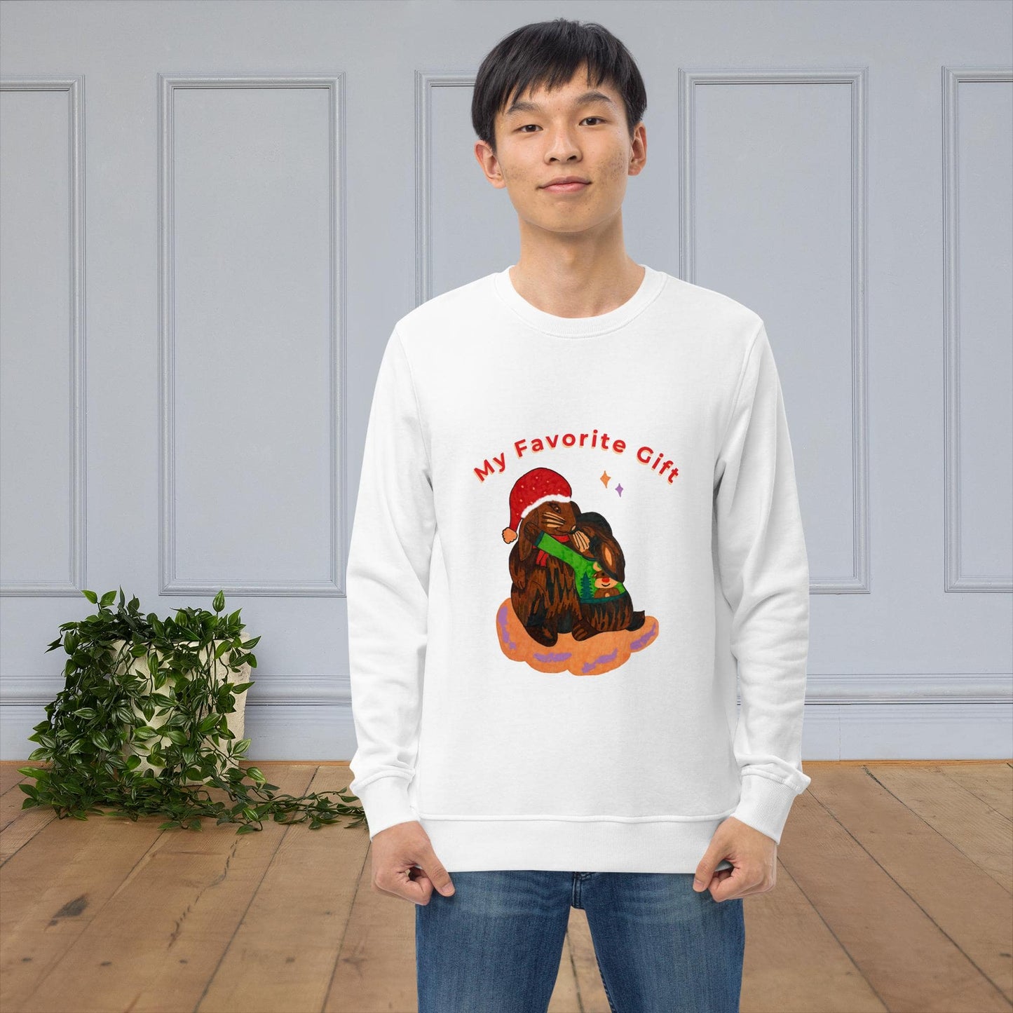 Man wearing a white sweatshirt with a Christmas-themed bunny design and text 'My favorite gift' in a room with a gray wall and wooden floor.