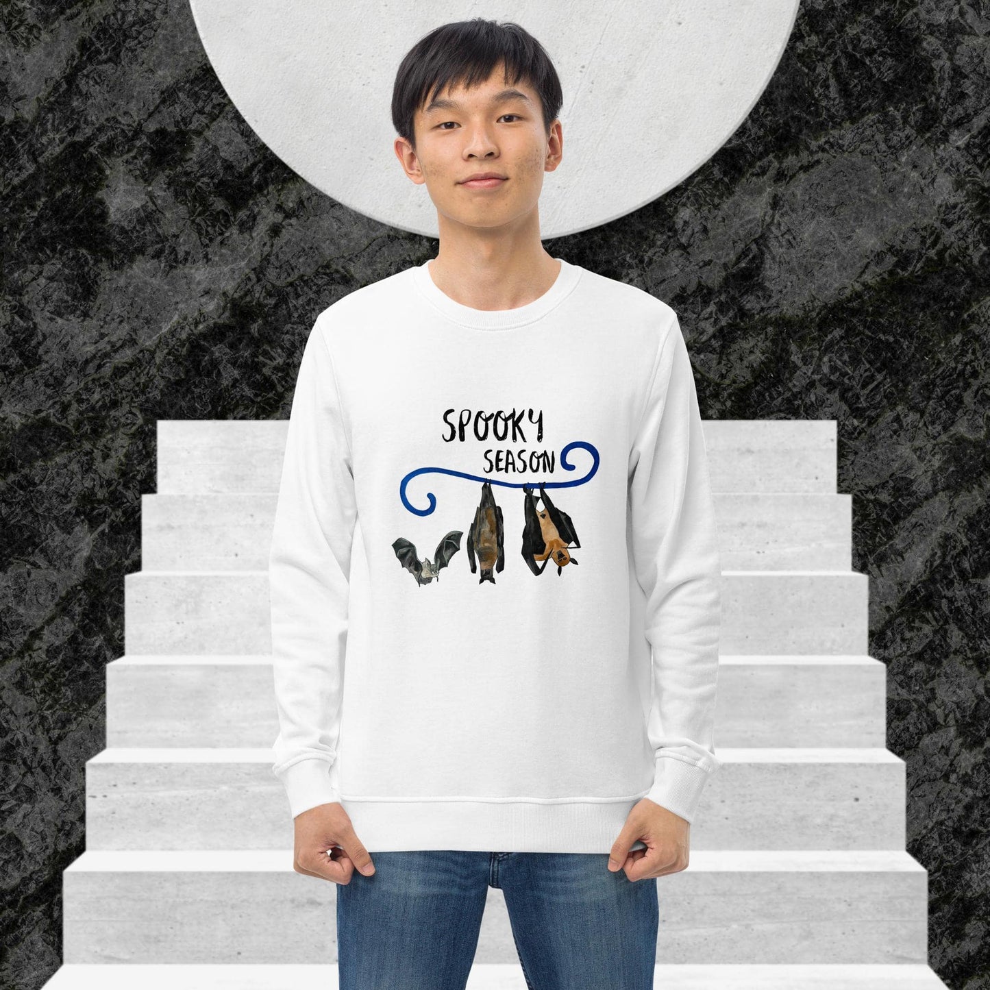 Man wearing a white sweatshirt with 'Spooky Season' design on a staircase background